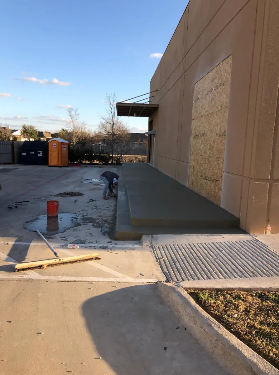 Freshly poured commercial concrete loading ramp beside a tilt-wall building