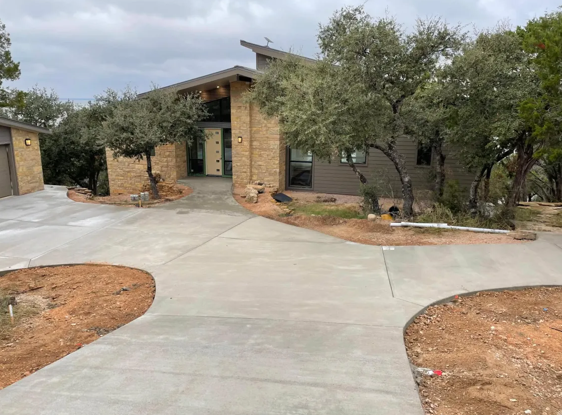 Curved residential concrete driveway leading to a modern stone home