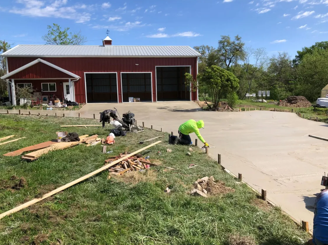New concrete driveway in front of a red barndominium