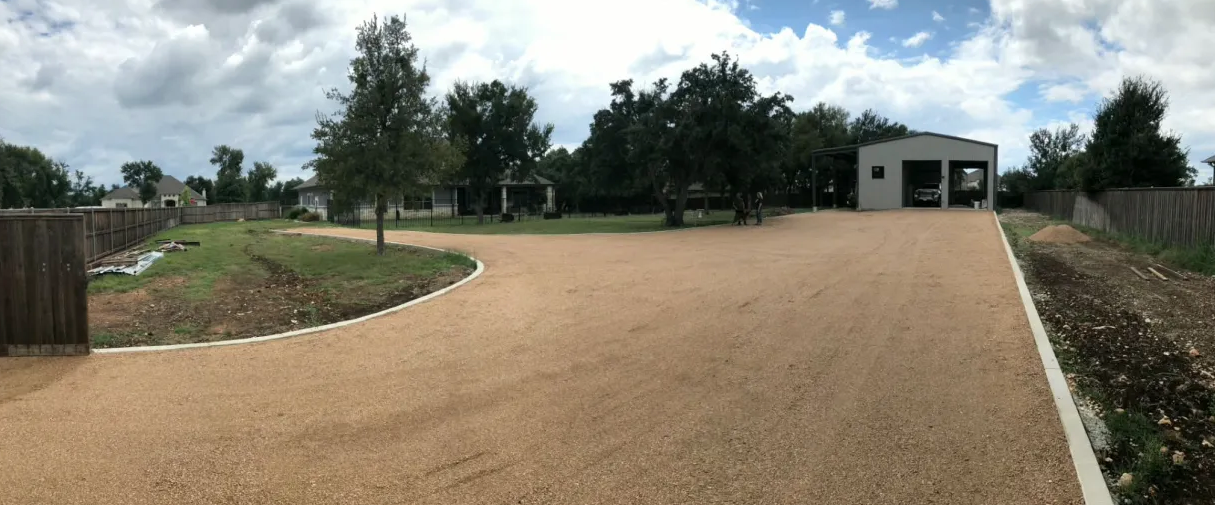 Wide curved driveway approach to a metal shop